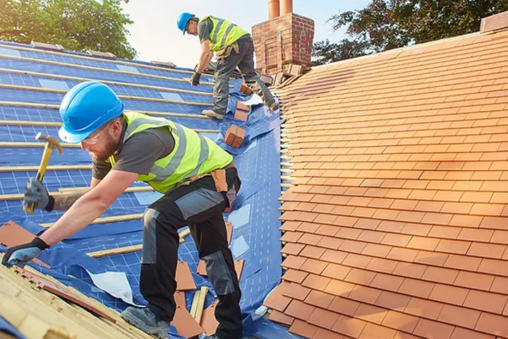 Pic showing two roofers replacing roof tiles on a house roof